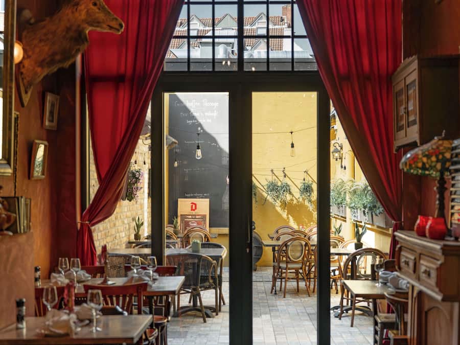 Restaurante com cortinas vermelhas, móveis de madeira e uma decoração com cabeça de veado.