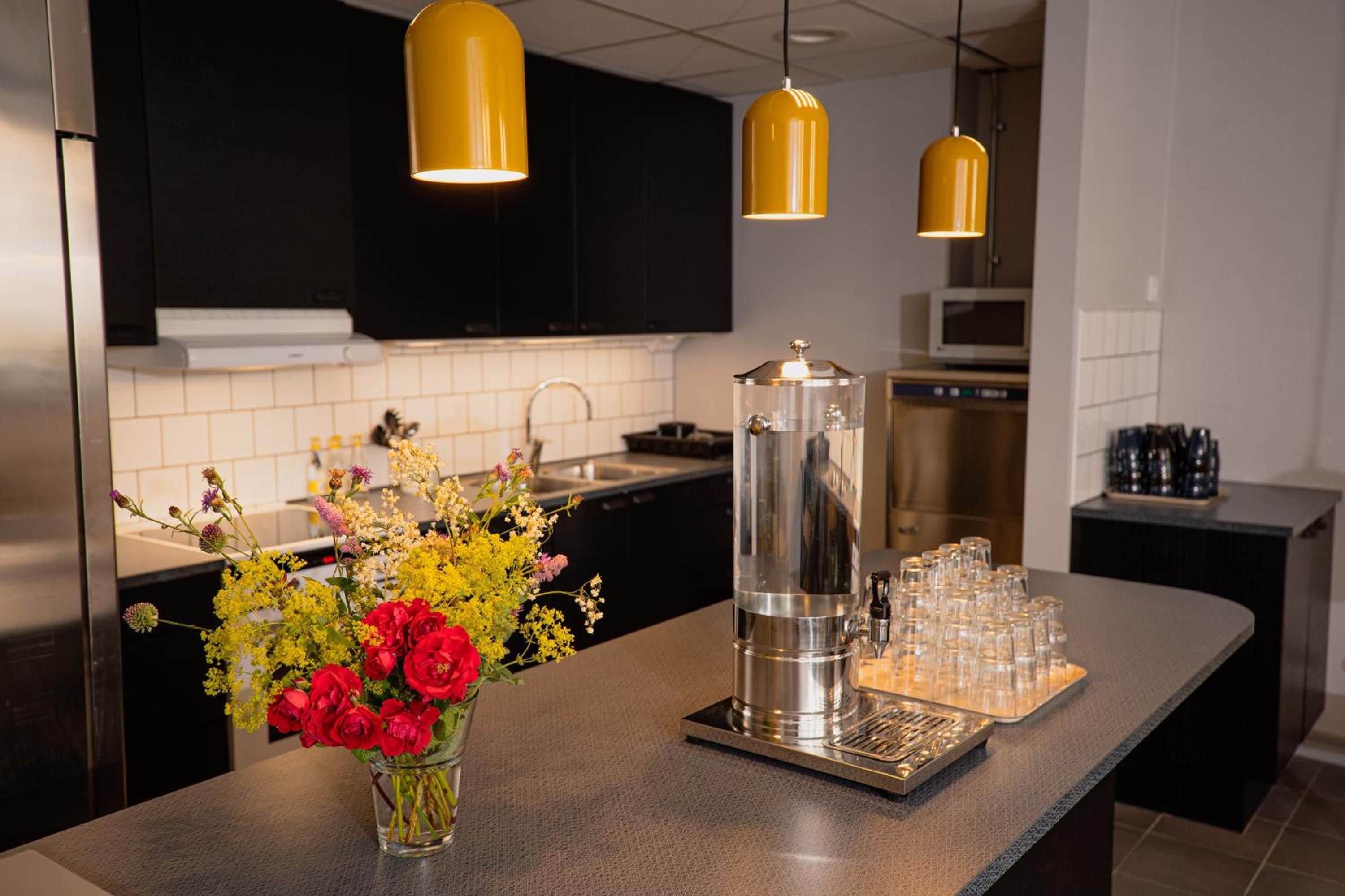Une cuisine moderne équipée d’une machine à café en acier inoxydable, d’une verseuse en verre et d’un plateau de verres.