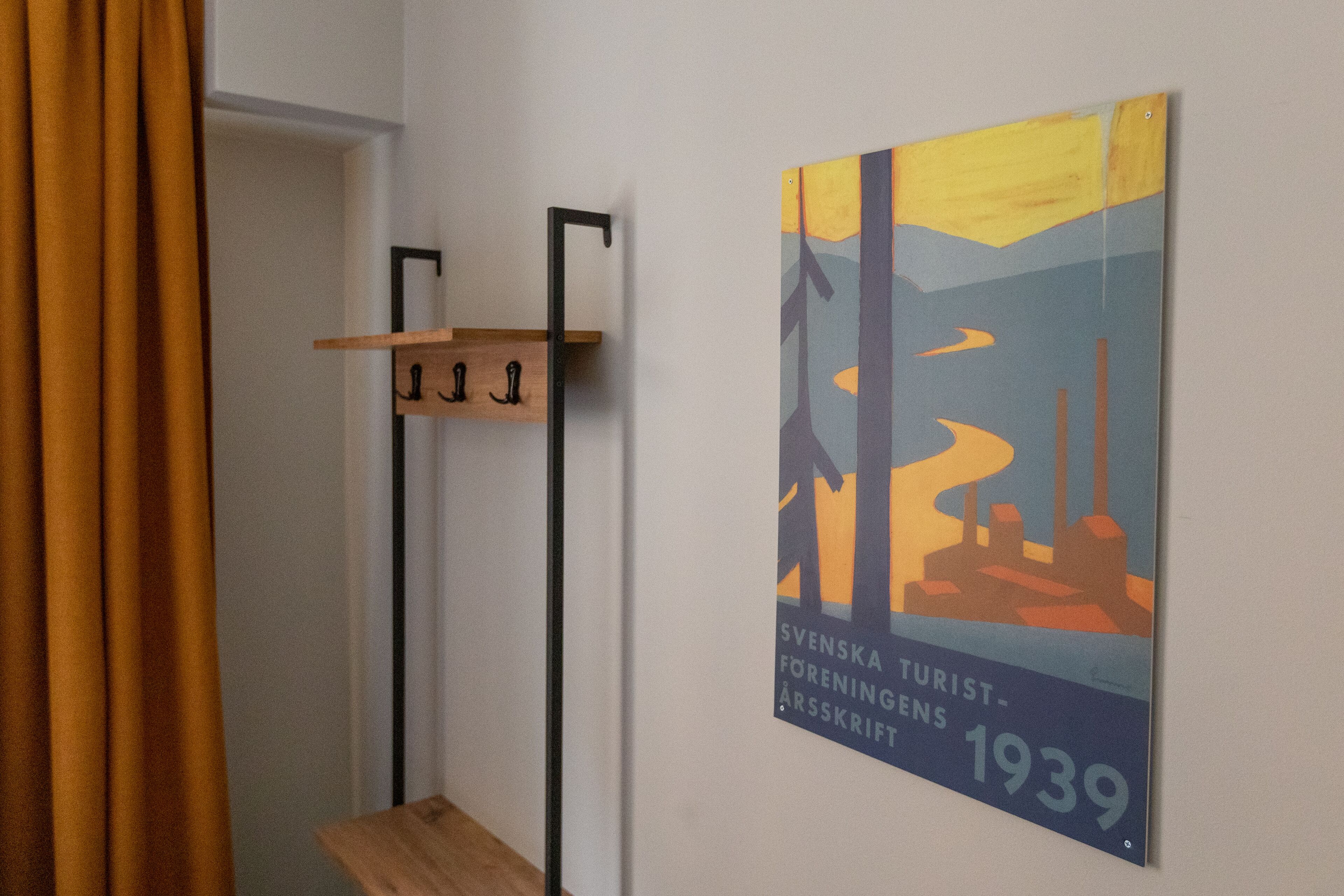 A corridor with a wooden bench, a coat rack, and a wall-mounted poster.