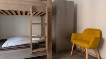 Ein Etagenbett mit Holzleiter, ein grauer Kleiderschrank und ein senfgelber Sessel.