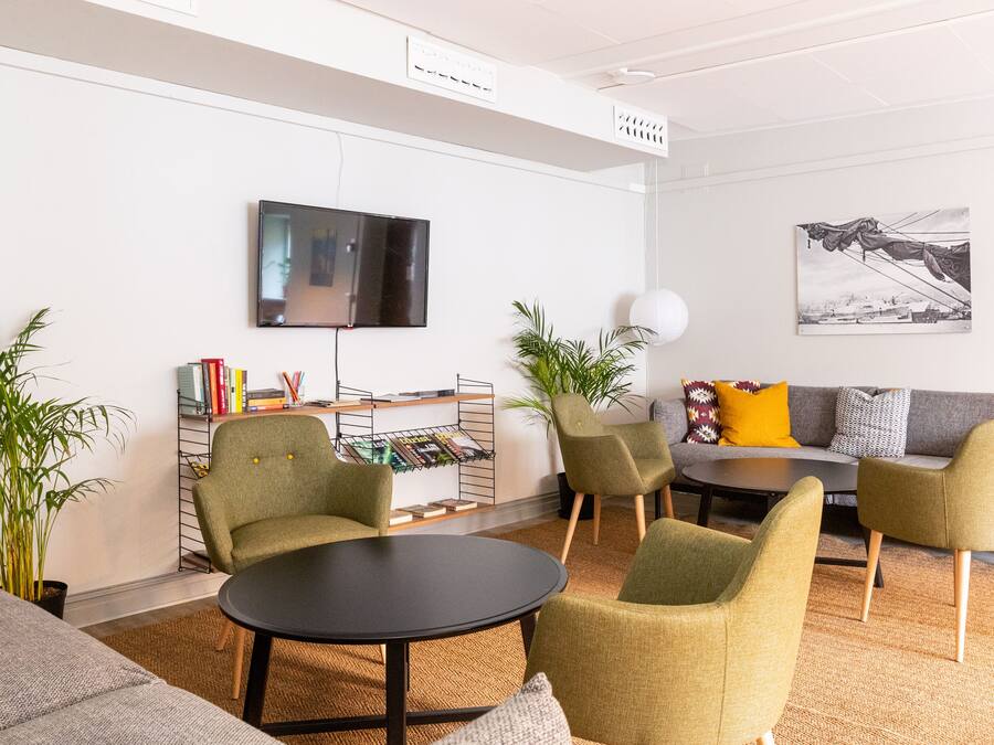 A modern living room with a flat-screen TV, a bookshelf, and a sofa with cushions.