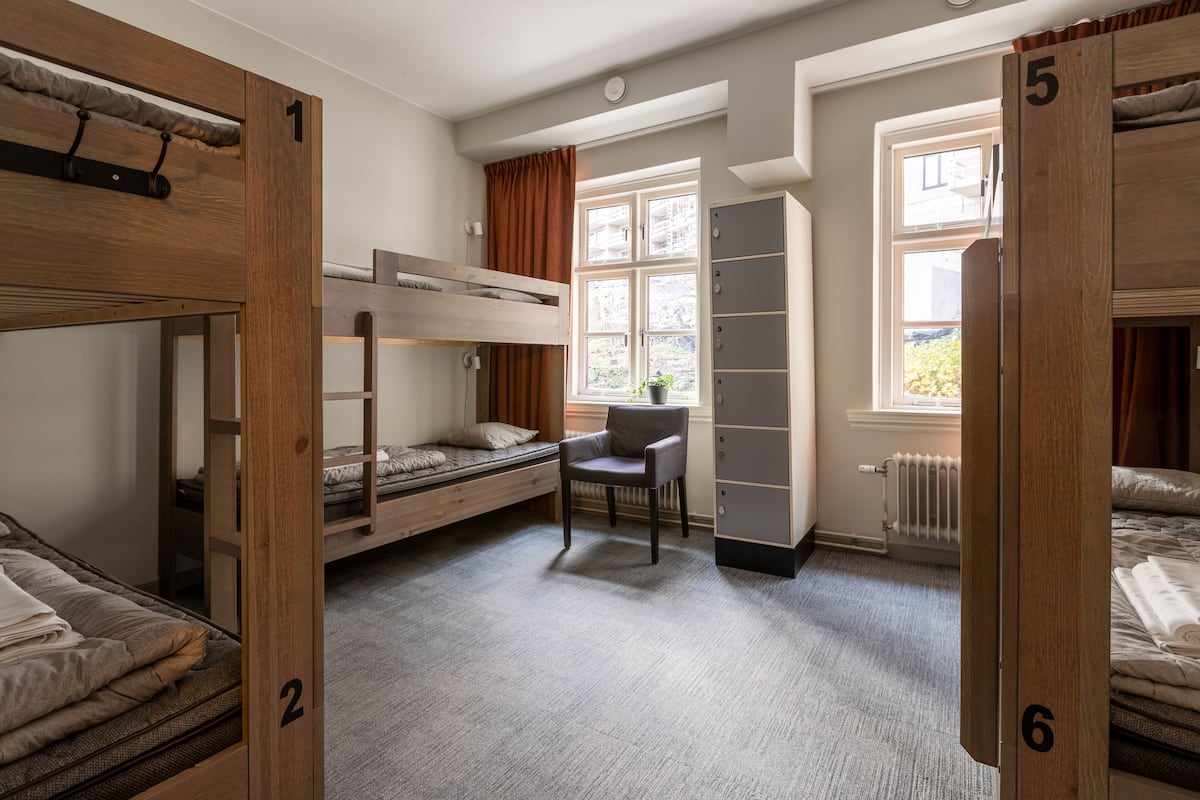A dormitory room with bunk beds, a desk, and a wardrobe.