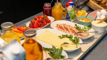 Een ontbijtbuffet met diverse gerechten, waaronder eieren, ham en tomaten.