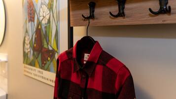 A red and black checkered shirt hanging on a wooden coat rack with hooks.