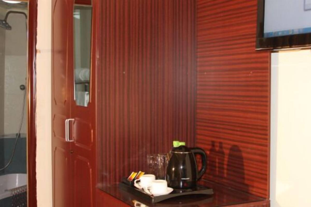 A hotel room with a red door, a small table with a coffee pot, cups, and a tray.