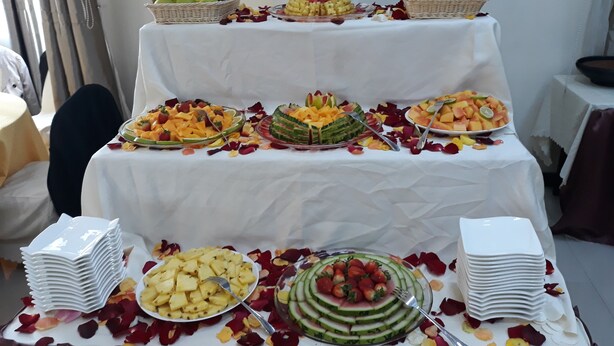 Mesa de buffet com diversas frutas e uma decoração central de abacaxi.