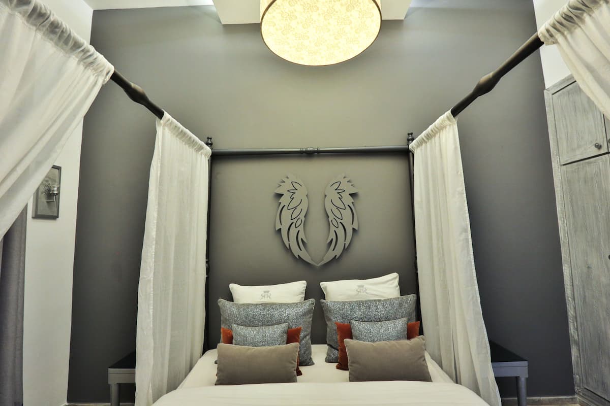Un dormitorio con cama con dosel, paredes grises y un elemento decorativo en la pared.