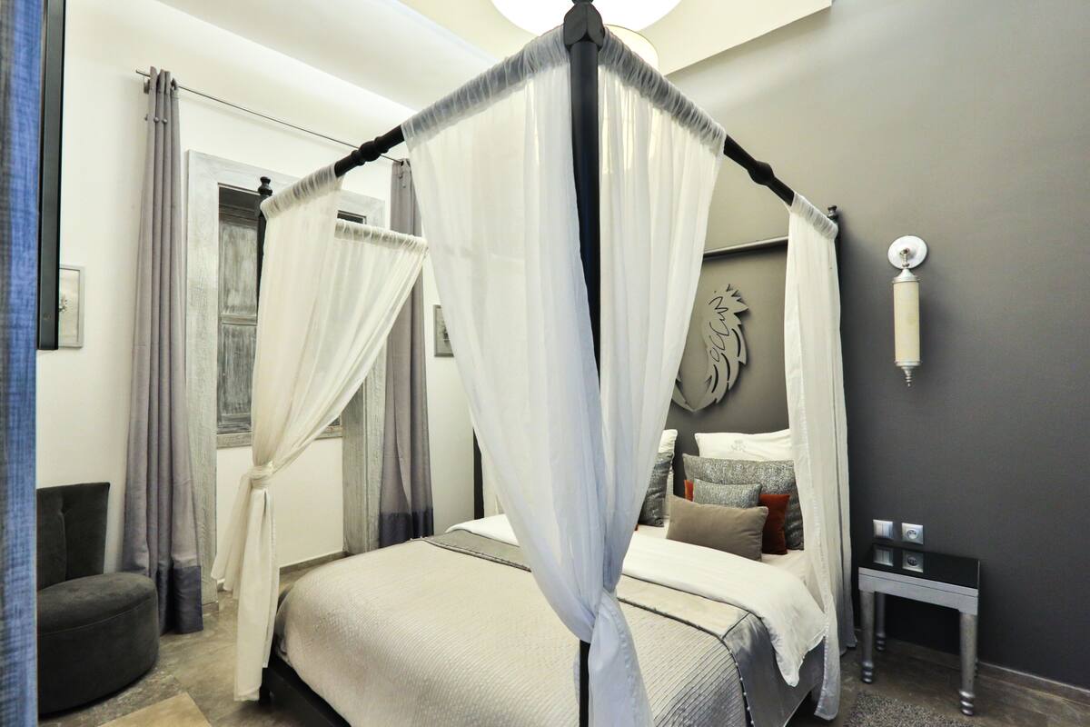 Un dormitorio con cama con dosel, una mesita de noche y una lámpara de pared.