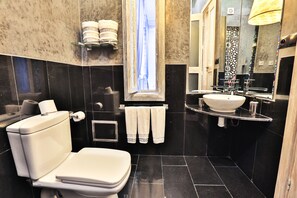 A modern bathroom with a toilet, sink, and large mirror.
