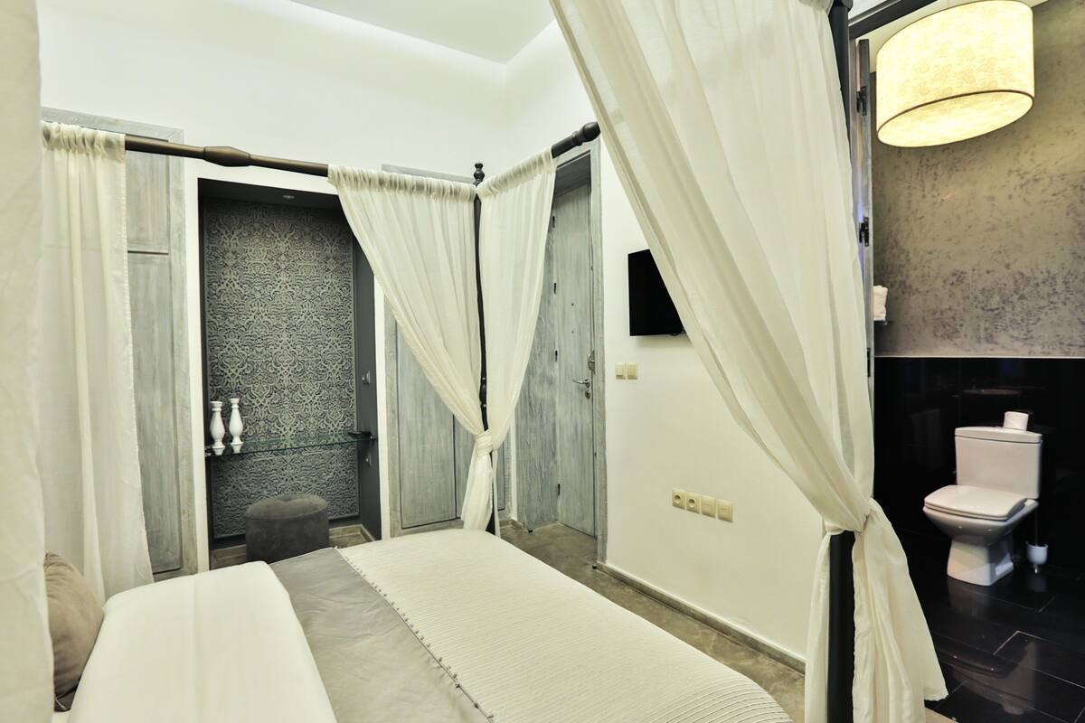 Un dormitorio con cama, un baño con inodoro y zona de ducha.
