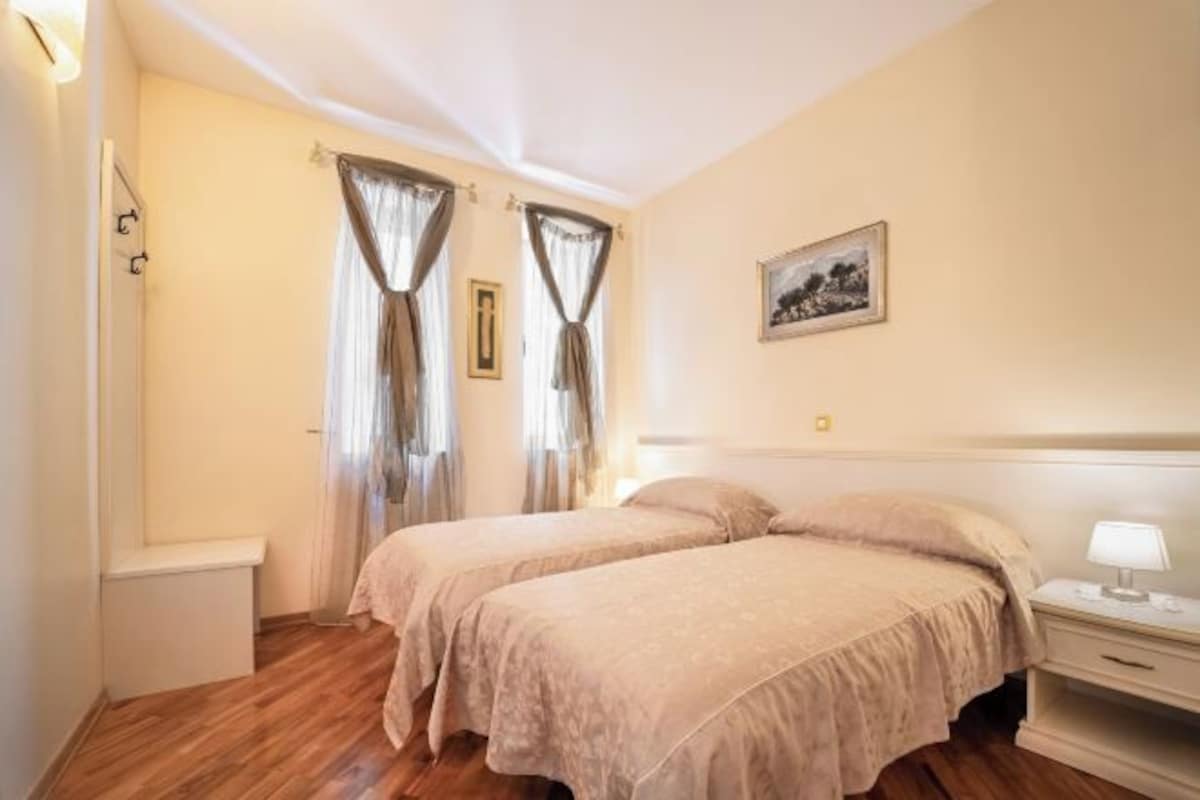 Un dormitorio con dos camas, una mesita de noche, una lámpara y un cuadro en la pared.