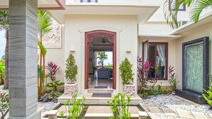 A well-maintained outdoor area with a stone pathway leading to a doorway, surrounded by various plants and a small water feature. - Casa de Balangan by Exotiq Villa Holidays (Jimbaran)