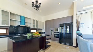 A modern kitchen with a central island, built-in appliances, and a chandelier. - Casa de Balangan by Exotiq Villa Holidays (Jimbaran)