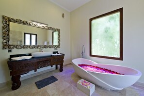 A bathroom with a freestanding bathtub, a large mirror, and a window. - Casa de Balangan by Exotiq Villa Holidays (Jimbaran)