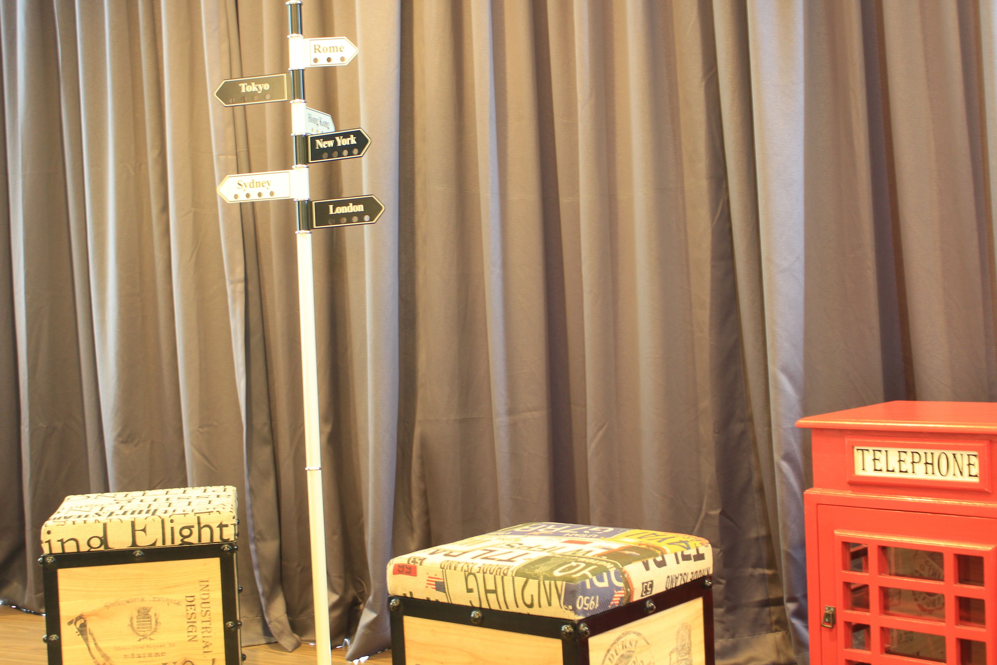A room with a directional signpost, a suitcase, and a red telephone booth.
