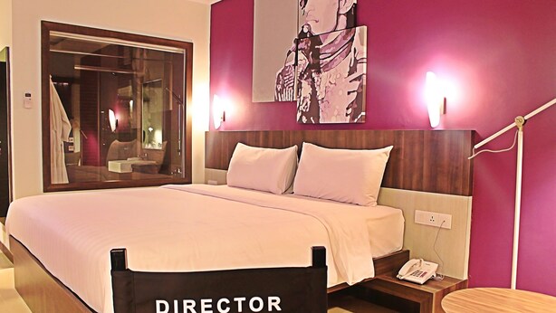 Habitación de hotel con una cama grande, una mesita de noche con teléfono, un espejo y una obra de arte colgada en la pared.