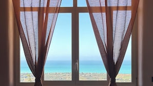 A room with a bed, a chair, and a window with curtains. - B&B La finestra sulla valle (Agrigento)