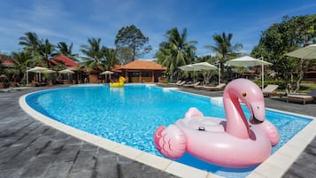 Relax by the pool surrounded by palm trees and lounge chairs.