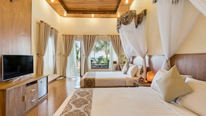 A hotel room with a wooden ceiling, two beds, a TV, a nightstand, and a view of palm trees. - Gold Coast Phu Quoc Resort (Phu Quoc)