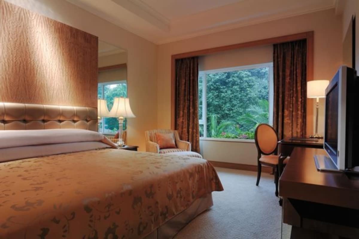 A hotel room with a large bed, a desk, a chair, and a television.