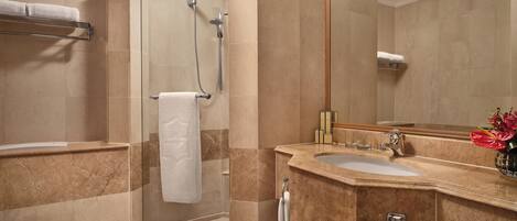 Un baño con ducha envuelta en vidrio, un lavabo e inodoro.