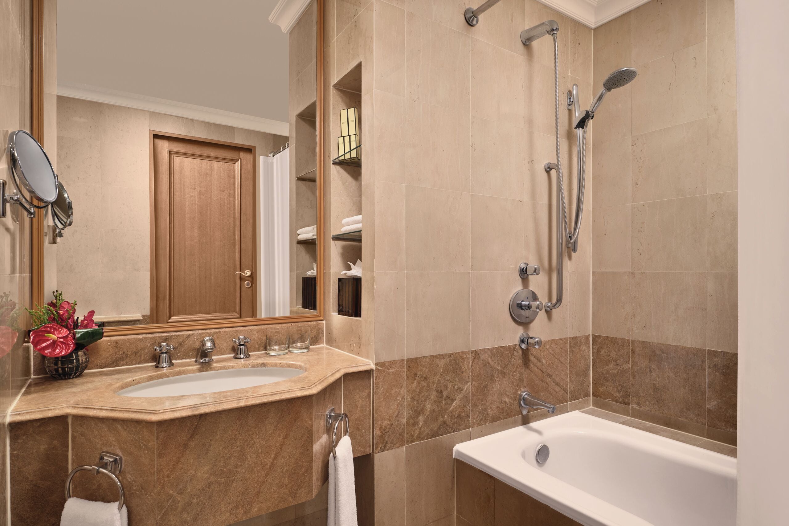 A bathroom with a sink, mirror, and shower.