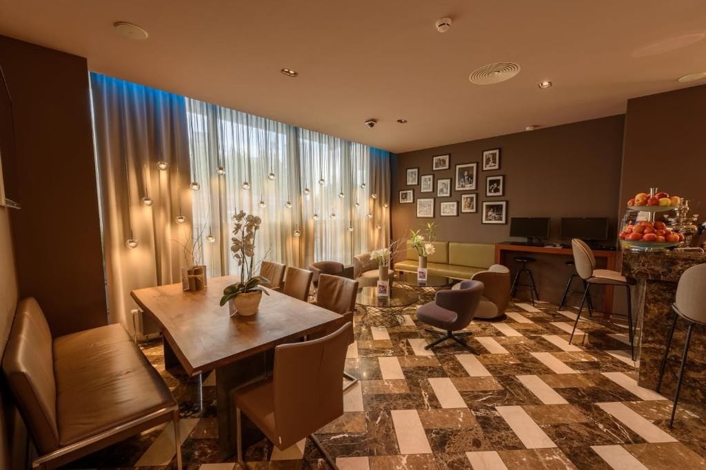 A hotel room with a dining area, a sofa, a TV, and a fruit display.