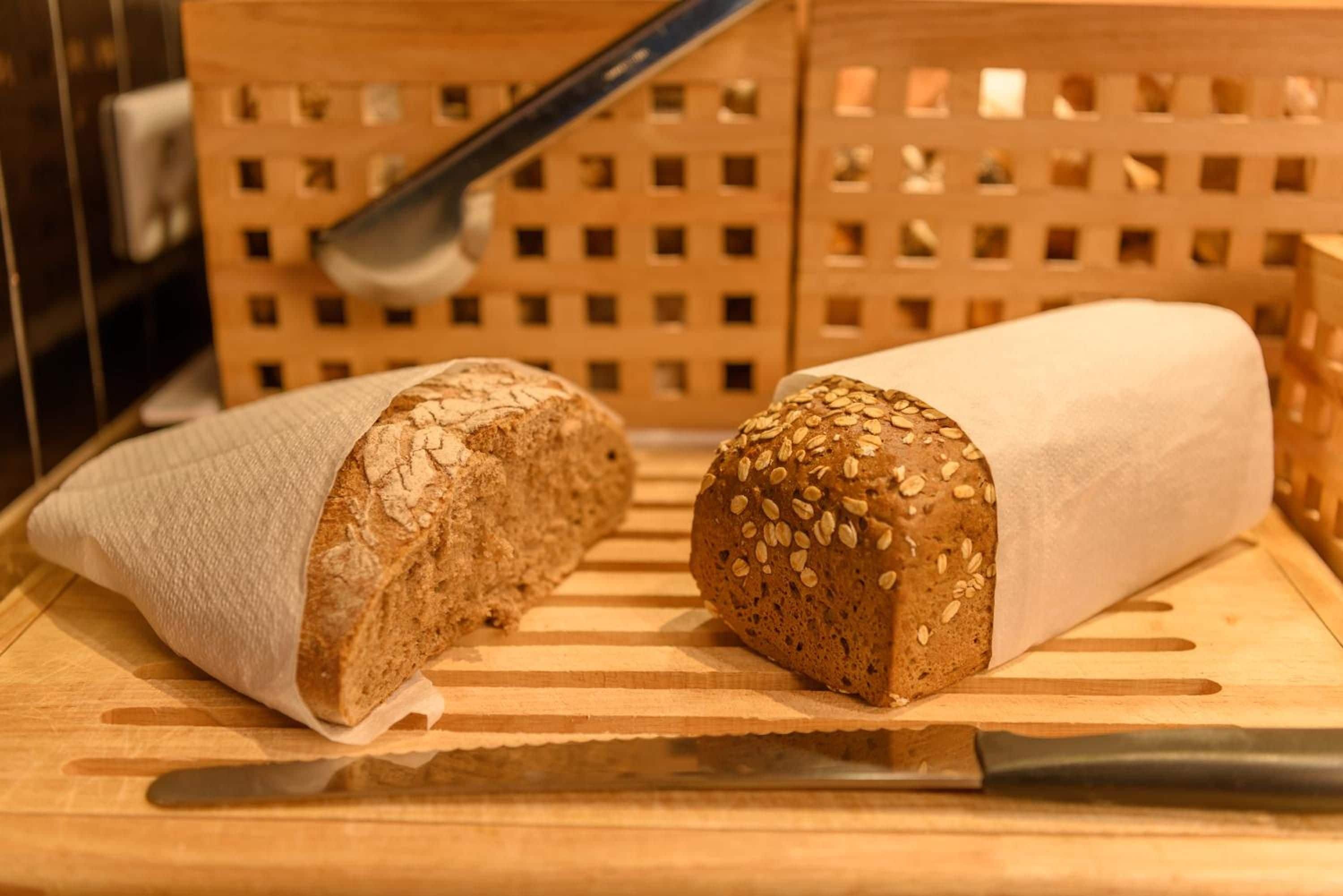 Two loaves of bread on a wooden cutting board with a knife.