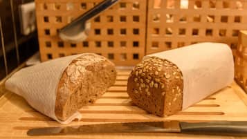 Two loaves of bread on a wooden cutting board with a knife.