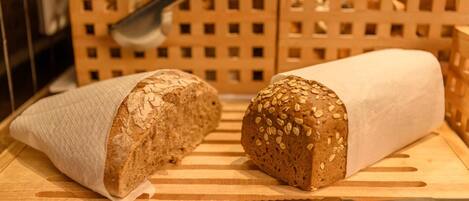 Two loaves of bread on a wooden cutting board with a knife.