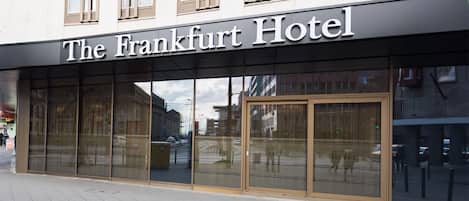 The Frankfurt Hotel with large glass windows and a modern facade.