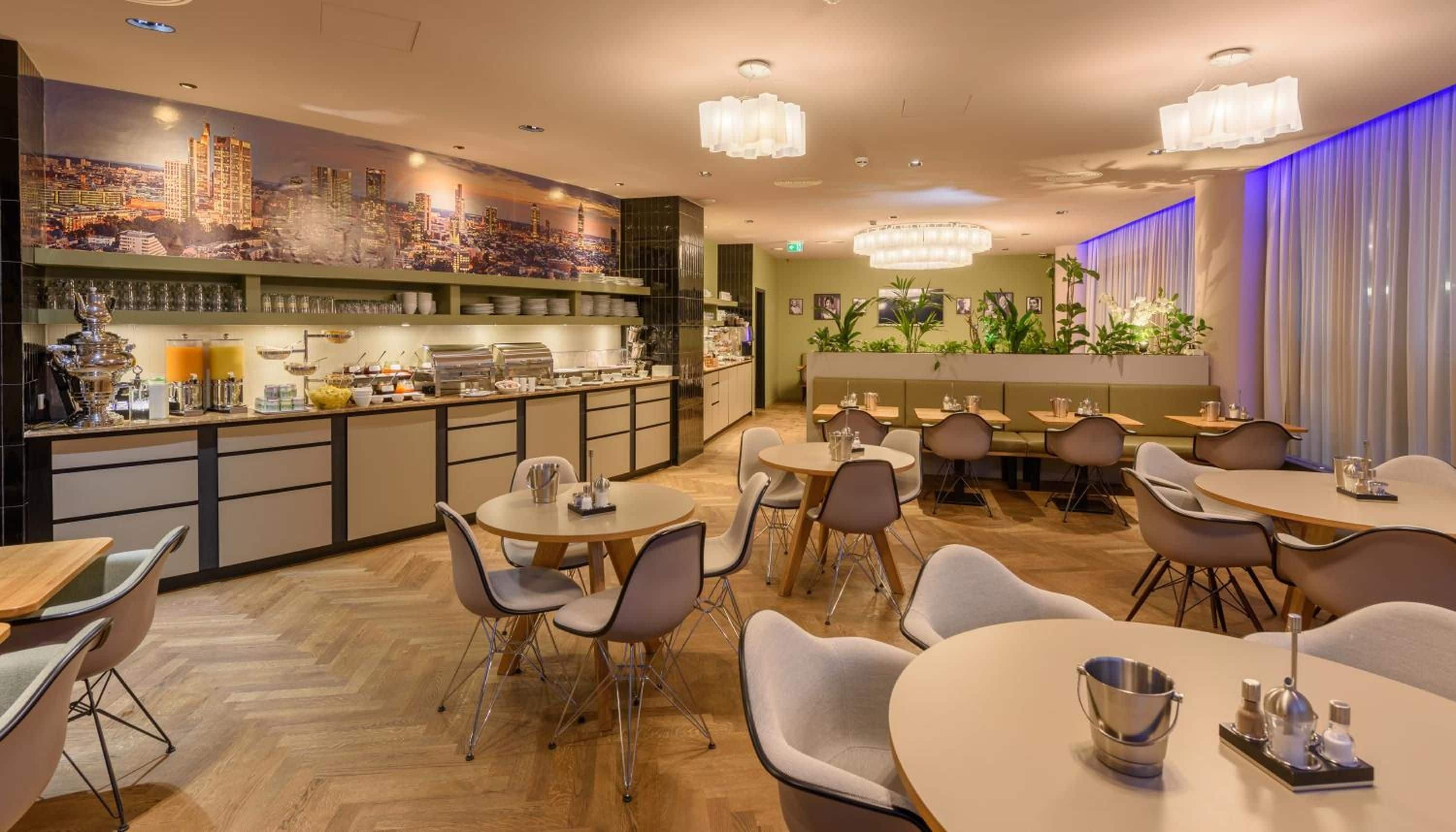 Un restaurante con zona de bar, distintas opciones de asientos y un mural de paisaje urbano en la pared.