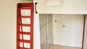 A room with a wooden ladder, a white door, and a ceiling-mounted light fixture. - Grampa's Hostel (Wroclaw)