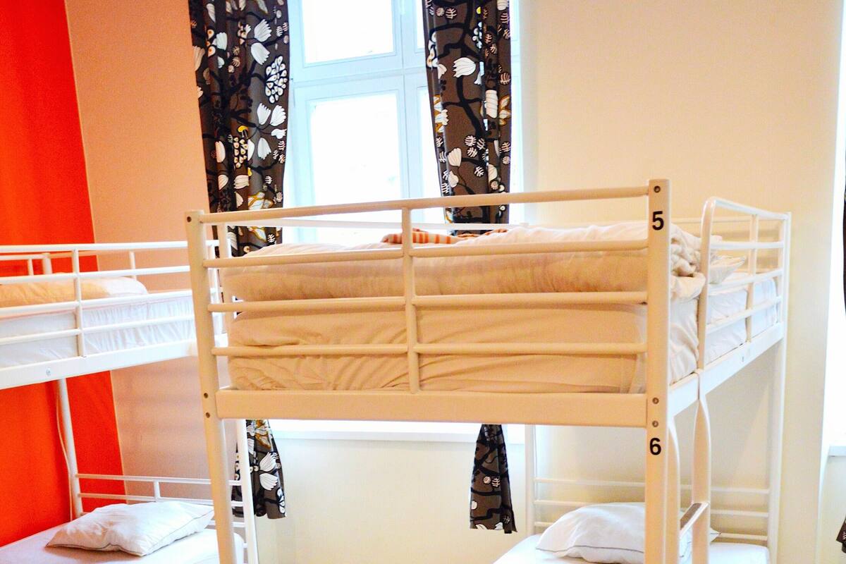Habitación con literas, una mesa y taburetes.