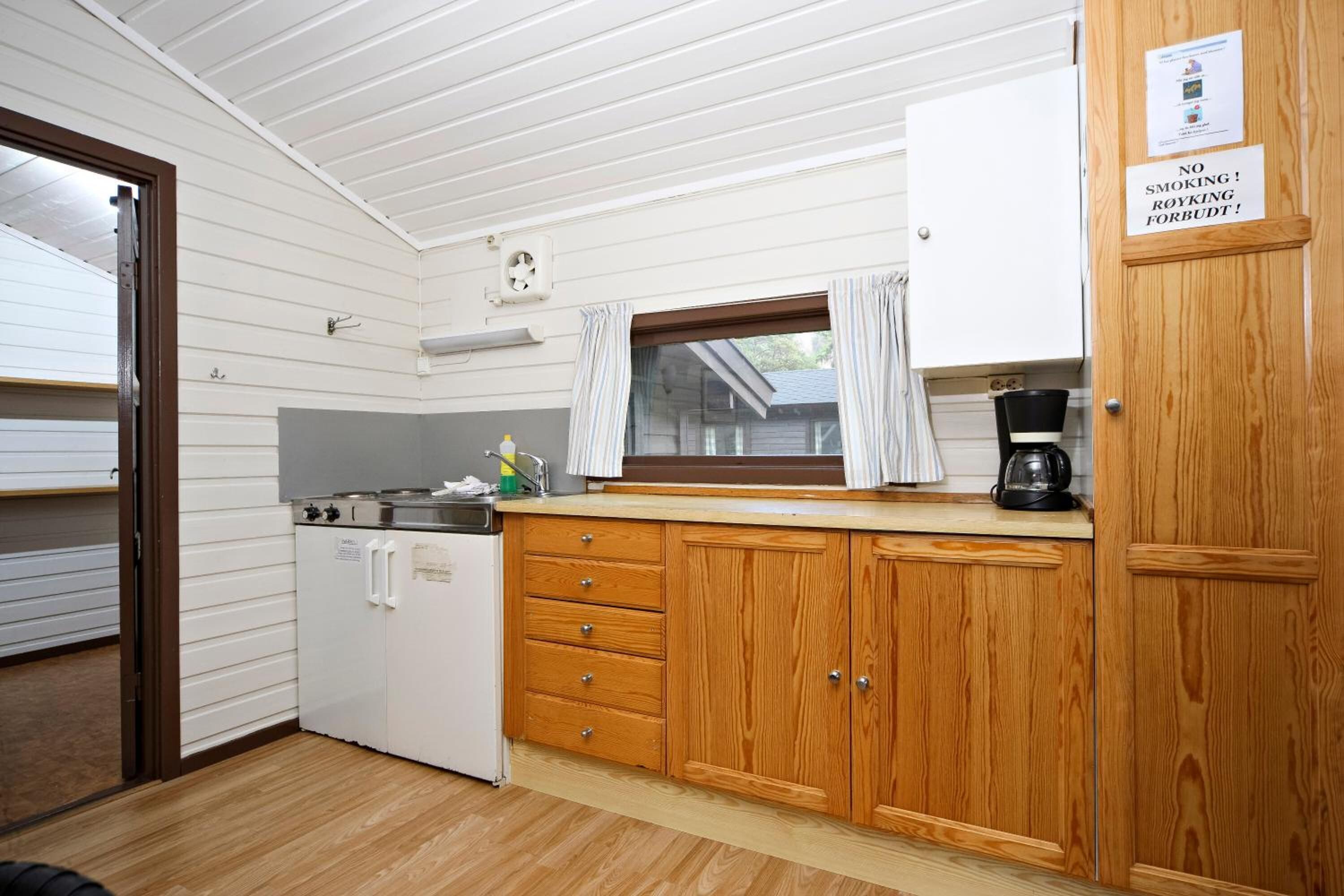 A compact kitchen with wooden cabinets, a white refrigerator, and a coffee maker.