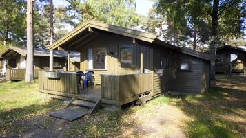 Une cabane en bois avec une véranda, une petite terrasse et une fenêtre.