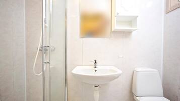 A modern bathroom with a glass shower enclosure, a white sink, and a toilet.
