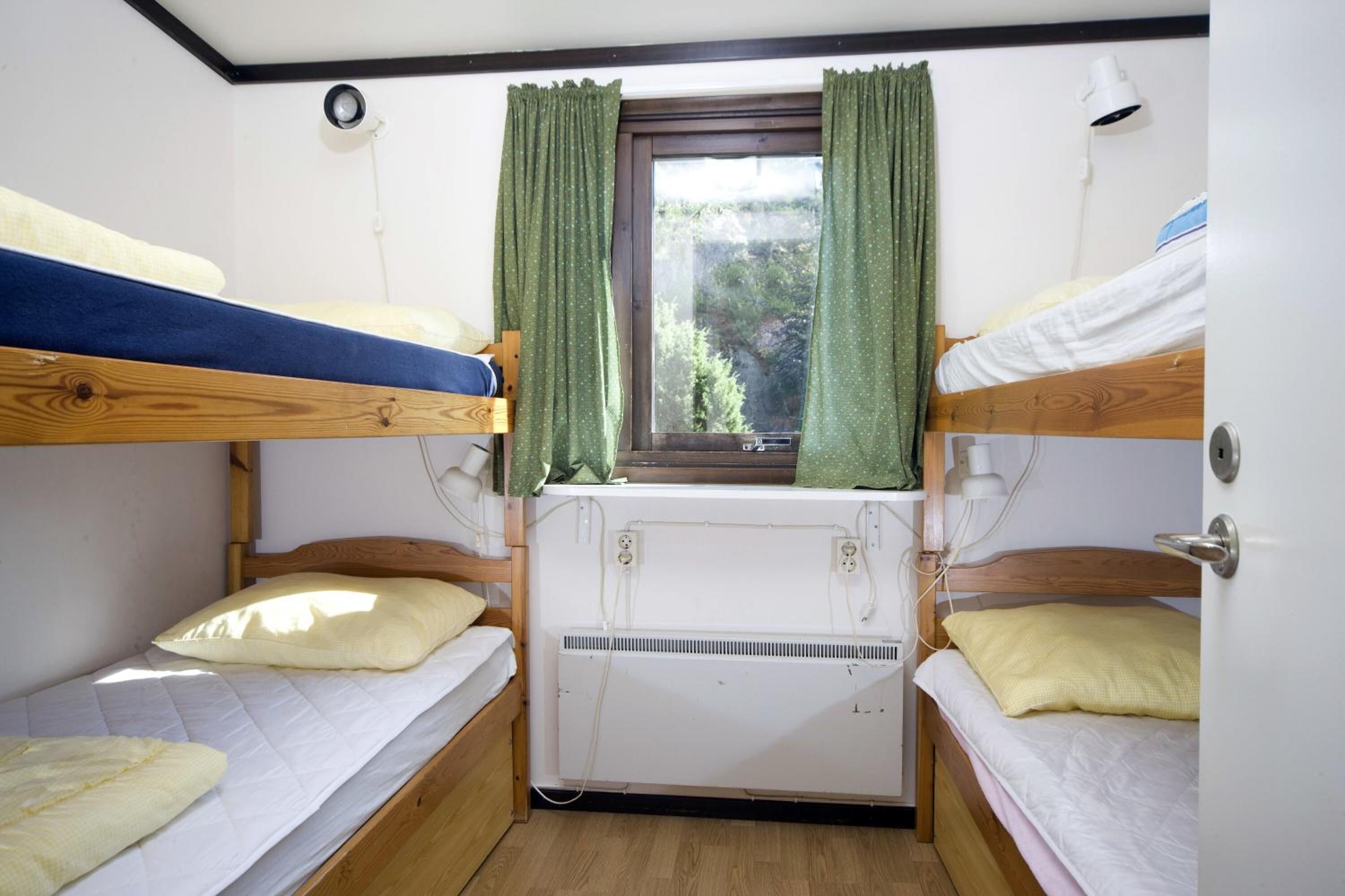 A bunk bed room with a window, a heater, and a lamp.
