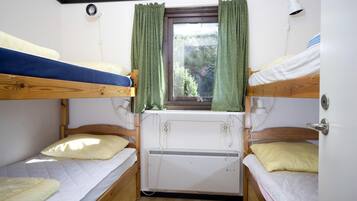 A bunk bed room with a window, a heater, and a lamp.