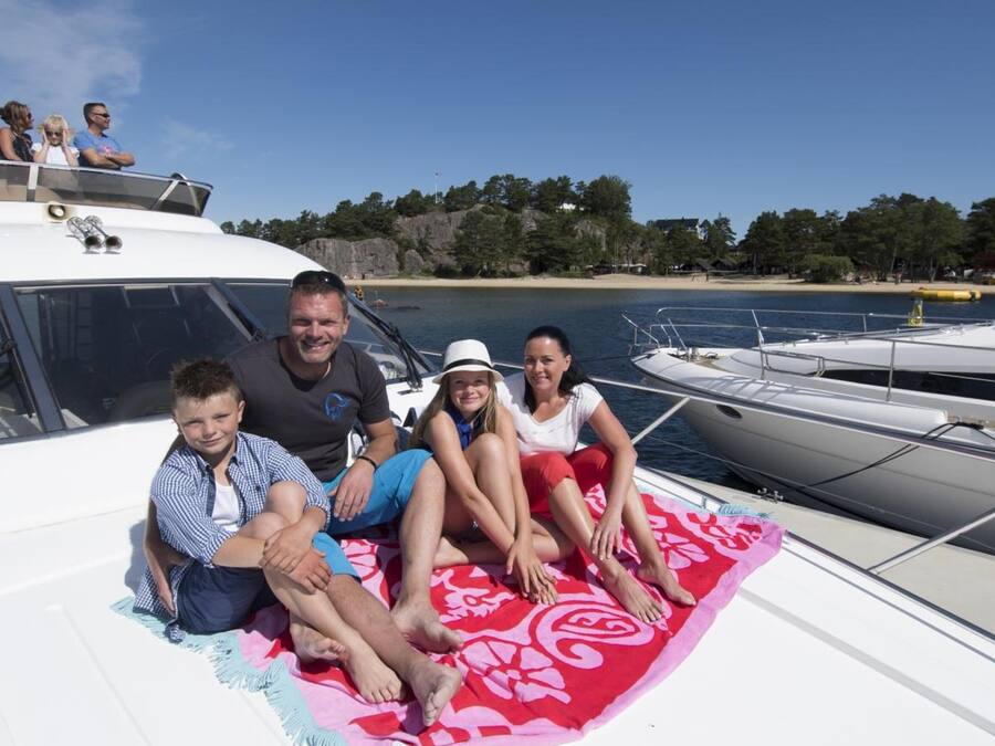 A family on a boat with a view of a beach and forest in the background.