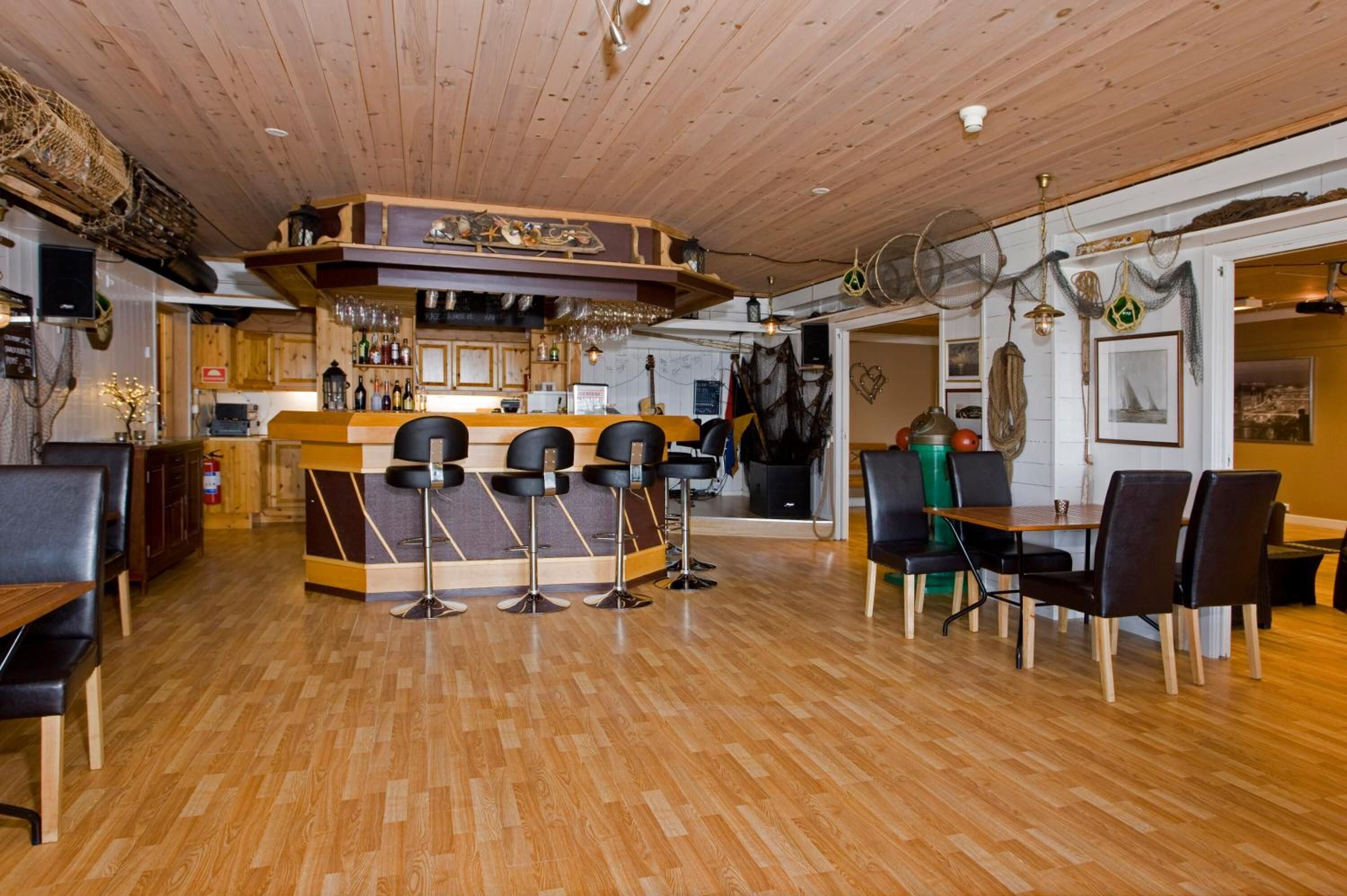 A restaurant with a wooden bar area, multiple seating options including bar stools and tables, and a wooden floor.