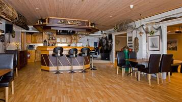 A restaurant with a wooden bar area, multiple seating options including bar stools and tables, and a wooden floor.