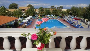 A poolside view with lounge chairs, umbrellas, and a clear blue sky. - Alkion Hotel Sidari (Corfu)