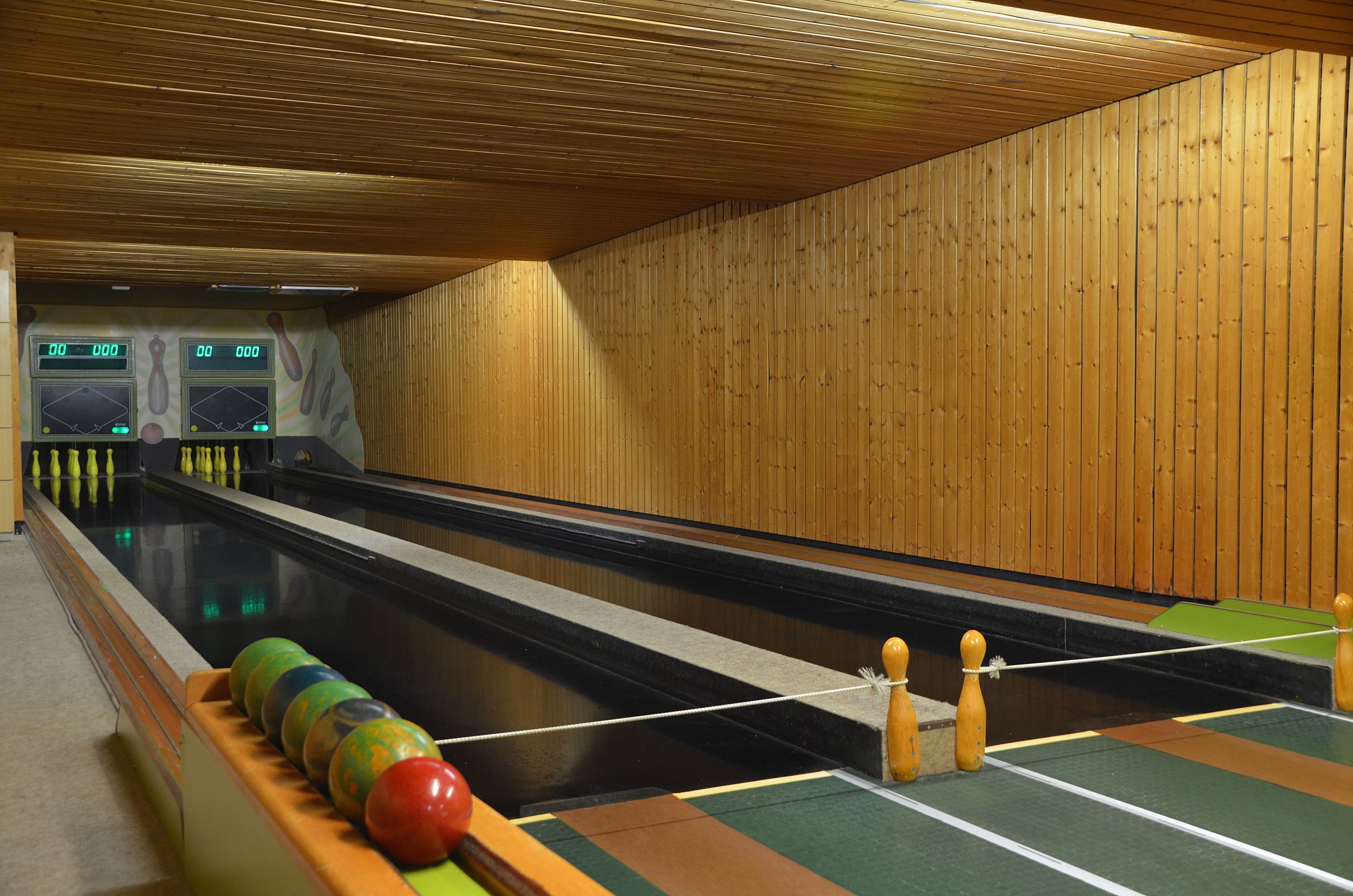 A bowling alley with wooden walls and a green carpeted floor.