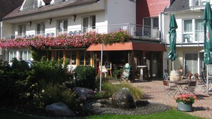 A hotel with a balcony adorned with flowers, a garden with a fountain, and outdoor seating. - Landhotel zur Linde (Lossburg)