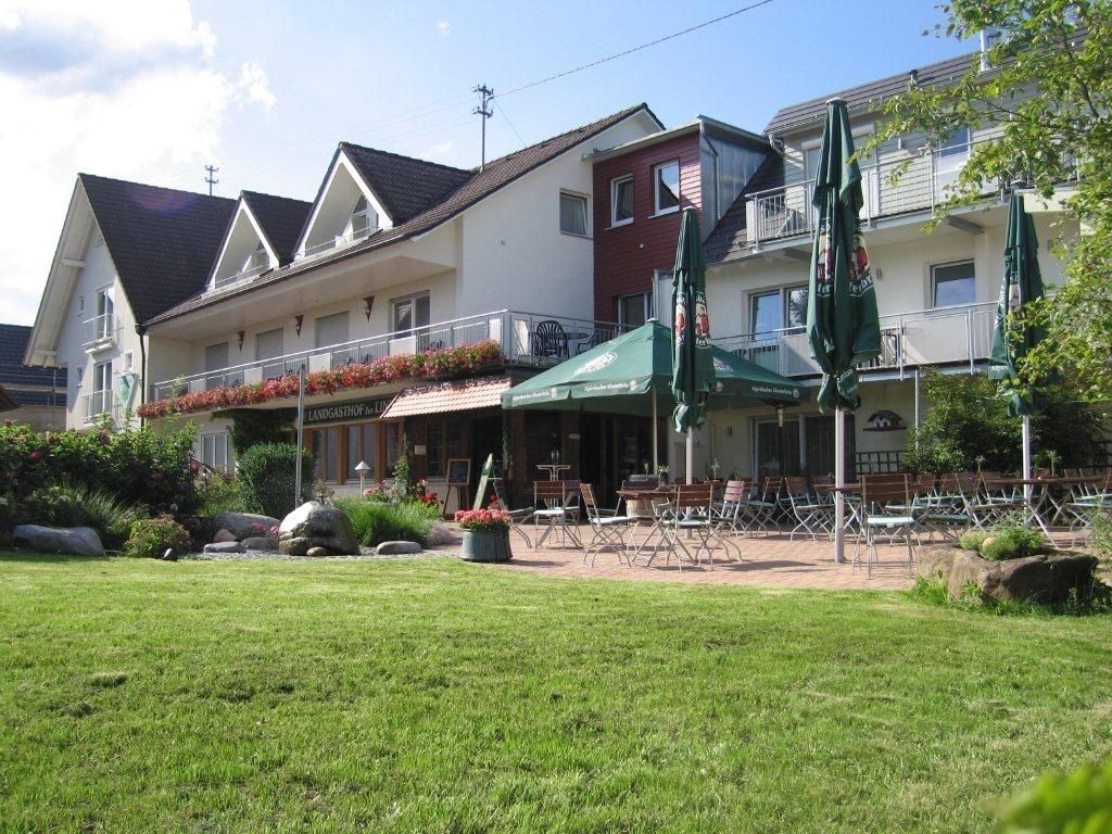 A building with a restaurant patio, outdoor seating, and a garden area.