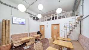A lounge area with seating, tables, and a staircase. - Hostel Orange (Prague)