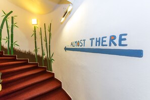 Una escalera con un mural que representa bambú y la frase "ALMOST THERE" con una flecha apuntando a la derecha.