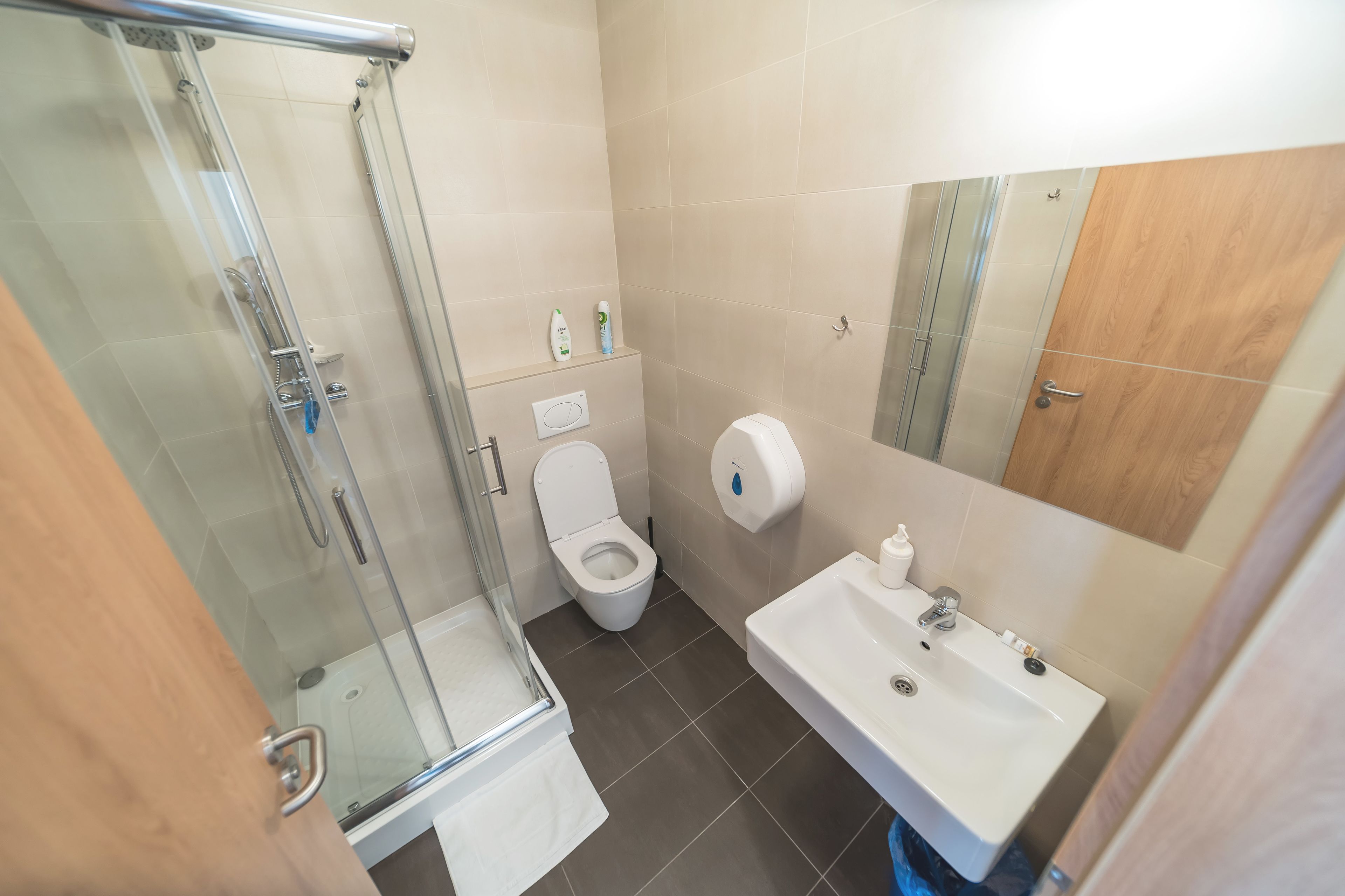 Un baño moderno con ducha de vidrio, inodoro y lavamanos con espejo.