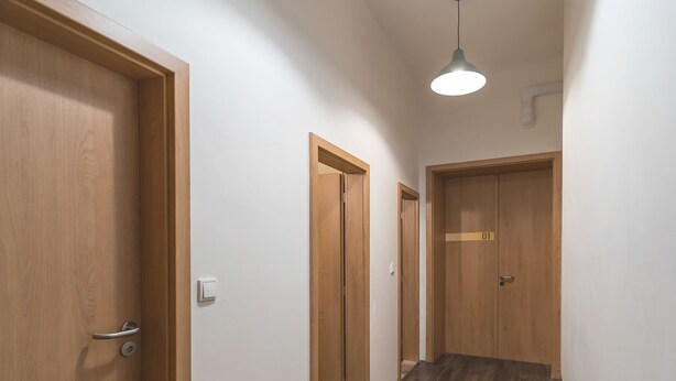 A hallway with wooden doors, a wooden floor, and pendant lighting. - Hostel Orange (Prague)